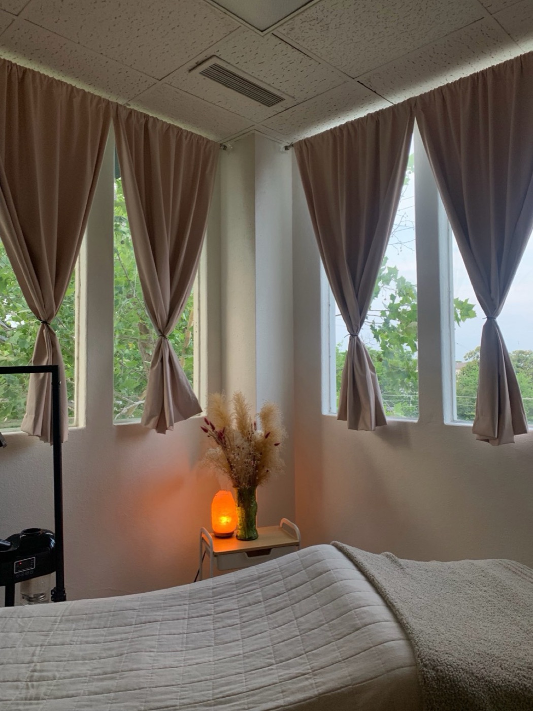 The treatment bed beneath curtained windows and a glowing salt lamp
